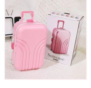 Mini salvadanaio a forma di valigia rosa con la sua confezione su sfondo chiaro