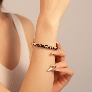 Close-up of a double-layered leopard print bangle on a model's wrist with knitwear