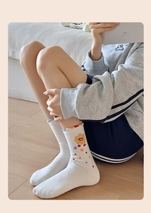 Détail de chaussettes blanches en coton avec broderie florale jaune et pois colorés
