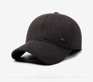 Detailed close-up of dark grey wool texture and metal logo plaque on winter baseball cap