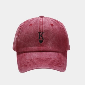 Detailed close-up of embroidered black K and heart on red washed cotton baseball cap