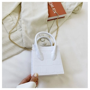 Close-up of white crocodile pattern PU leather handbag with elegant gold chain strap detail
