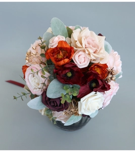 Top view of a red and orange artificial bridal bouquet with roses and golden accents