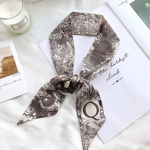 Detail of the letter Q silk scarf with moon and star prints on a soft white background