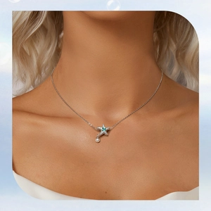 Close-up of a s925 silver starfish necklace with green stone and pearl on a model