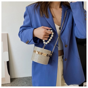 Detail of champagne gold pearl mini box bag shown with chain strap on a model