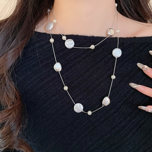 Detail of layered vintage acrylic pearl and crystal necklace on a dark knit garment
