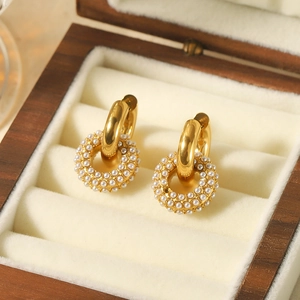 Close-up of gold hoop earrings with white pearl donut charm in a luxury jewelry box