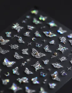 Makroaufnahme von 3D-Nagelstickern mit irisierenden Schmetterlingen und Perlenbesatz