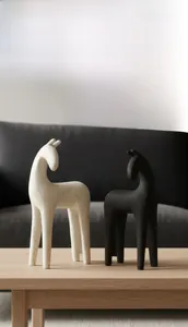 Detailed texture of minimalist black and beige resin horse statues on wooden table