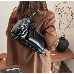 Vue de dos d'un sac à bandoulière vintage noir brillant avec plusieurs zips sur un mannequin