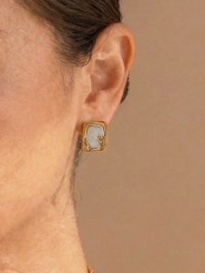 Detailaufnahme eines rechteckigen Goldohrrings mit weißer Marmortextur an einem Model