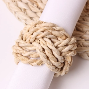 Macro detail of natural straw woven napkin ring featuring a rustic braided knot design