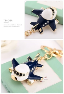 Detailed view of airplane keychain with navy enamel and inlaid rhinestones on golden metal