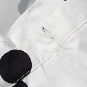 Détail de la fermeture éclair invisible et du tissu sur l'ensemble blanc à pois noirs