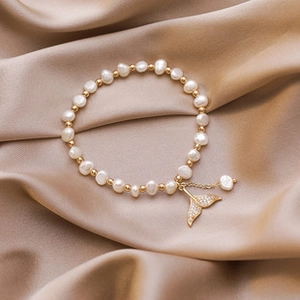 Macro detail of 14K gold plated bracelet with baroque pearls and crystal fishtail charm