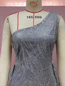 Detailansicht glitzernder Silberpailletten mit Sandstruktur auf einem grauen Abendkleid