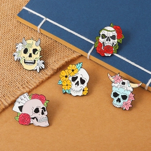 Detail of five punk skull enamel pins featuring roses and bull heads on varied textures