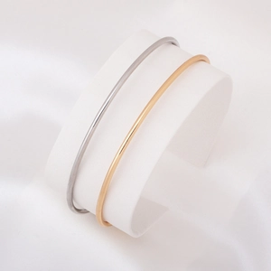 Minimalist gold and silver heart bracelets displayed on white silk for jewelry presentation