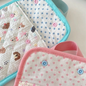 Close-up of quilted cotton pouches with floral dog and polka dot prints with ribbon handles