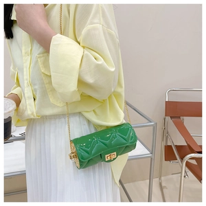 Close-up of green quilted cylindrical jelly bag with gold chain strap on a model