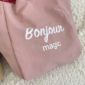 Detail of light pink tote bag featuring Bonjour magic text on fuzzy white background