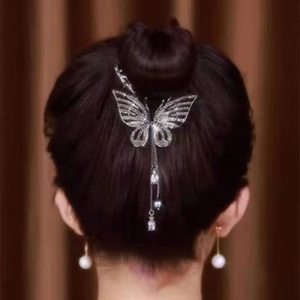 Detailed view of a silver butterfly hair clip with rhinestones and long tassels on a bun