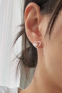 Detailed view of silver heart earrings featuring elegant white pearls and a minimalist design