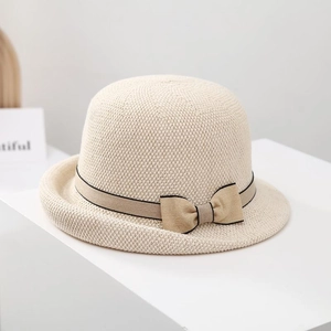 Detailed macro view of cream woven sun hat featuring a khaki ribbon and chic bow