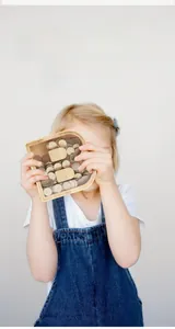 Detail of wooden letter B piggy bank with coins and transparent glass panel