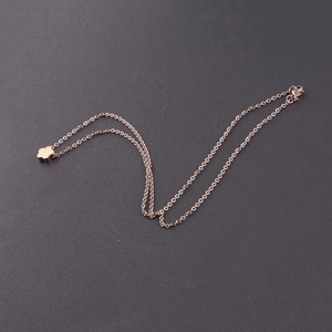 Detail of rose gold flower pendant necklace on a dark matte surface in diagonal view