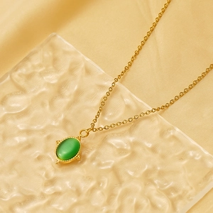 Gold stainless steel sun necklace with green cat-eye stone on textured glass surface