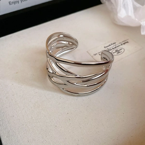 Detail of layered wavy hollow silver bangle with polished finish and French style design