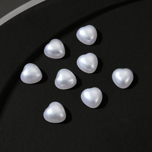 Close-up of eight 3D white pearl heart charms for nail art and phone case decoration