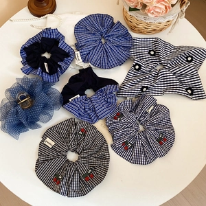 Détails de chouchous à carreaux bleus et noirs avec broderie cerise sur une table blanche
