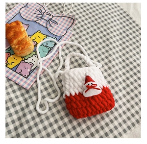 Flat lay of a knitted red Christmas deer bag with Santa 3D detail on checkered cloth