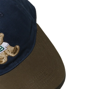 Close-up of embroidered bear pattern and navy blue cotton fabric on a baseball cap
