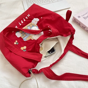 Detail view of red canvas tote interior with zipper pocket and embroidered happy lettering