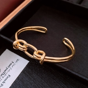Dettaglio macro di un bracciale rigido dorato ovale con design a catena su scatola nera