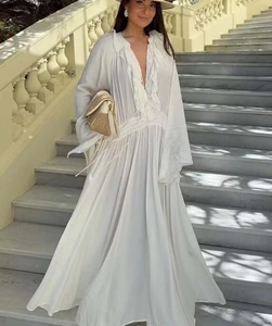 Detail of a white V-neck maxi dress featuring ruffled edges and bohemian flared sleeves