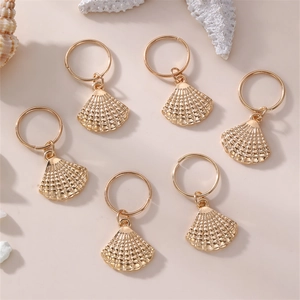 Detail of six golden seashell hair rings arranged on a marine-themed beach background