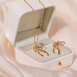 Detail of bow-shaped zircon pendant necklace and earrings set in a white jewelry box
