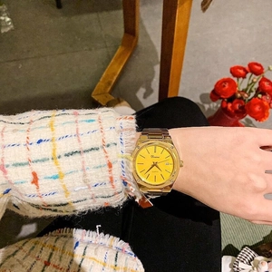 Close-up of golden quartz watch with yellow dial and date display on a wrist