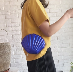 Dettaglio della borsa a tracolla a conchiglia blu scuro con catena dorata e perla