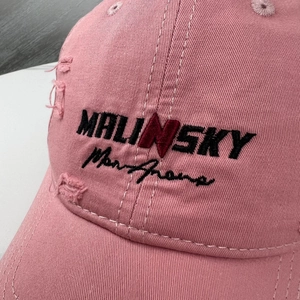 Detail of pink distressed baseball cap with 3D embroidery and vintage ripped texture
