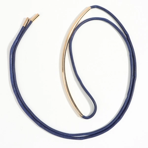 Detail of dark blue woven cord necklace with curved gold metallic tube and end caps