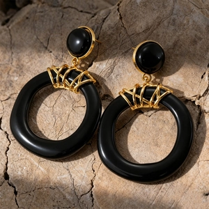 Detail of vintage black resin hoop earrings with textured gold-tone wire wrap on a rock