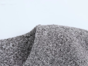 Vue macro de la texture du tissu bouclé gris montrant le tissage de la veste d'hiver