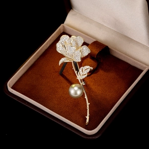 Detail of a luxury gold rose brooch with zircon crystals and a hanging white pearl