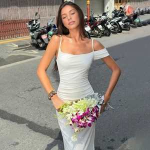 Detail of white bodycon maxi dress featuring side ruching and backless design on street